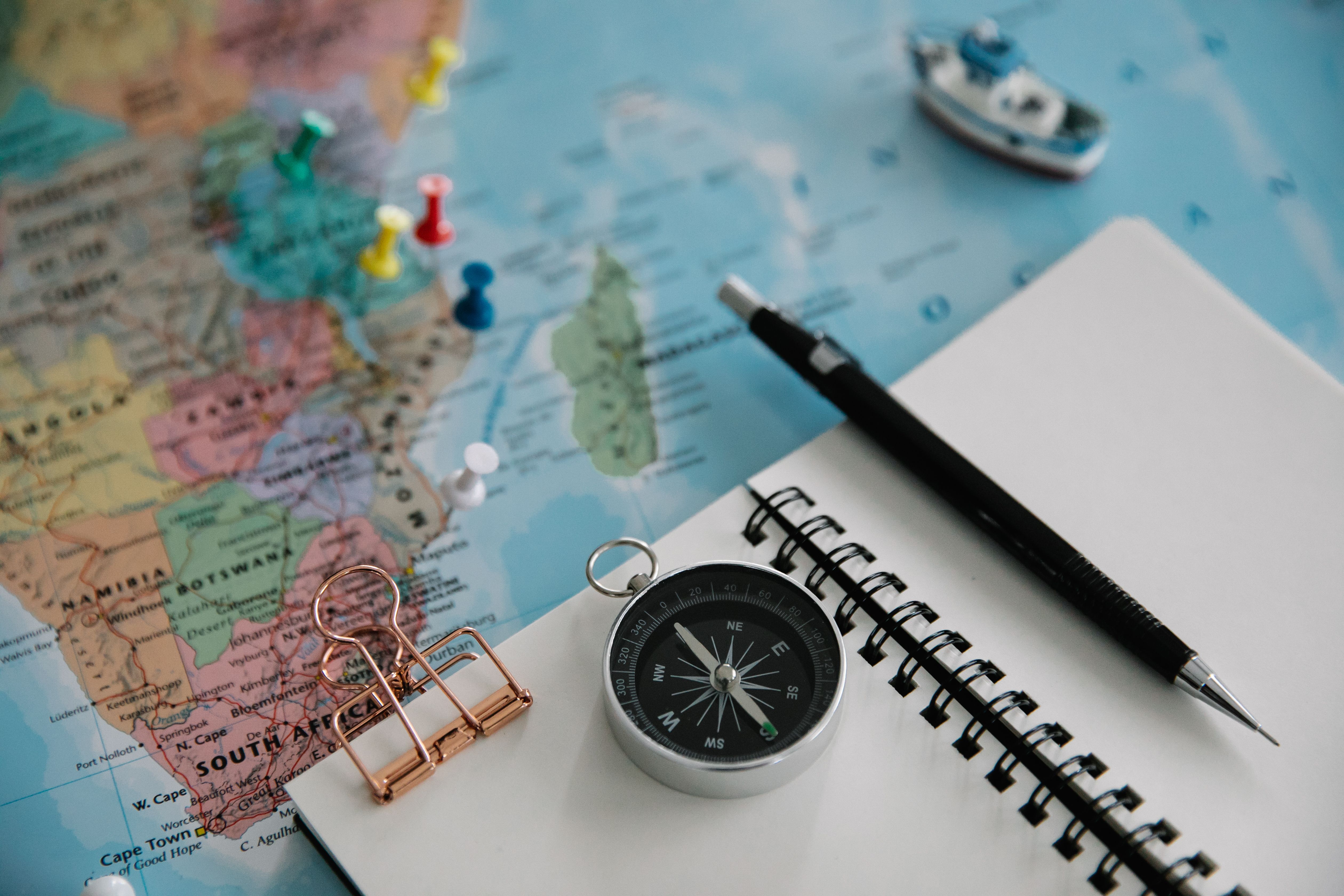 Flat lay of a map, compass, notebook and pen used to plan an adventure within set limits