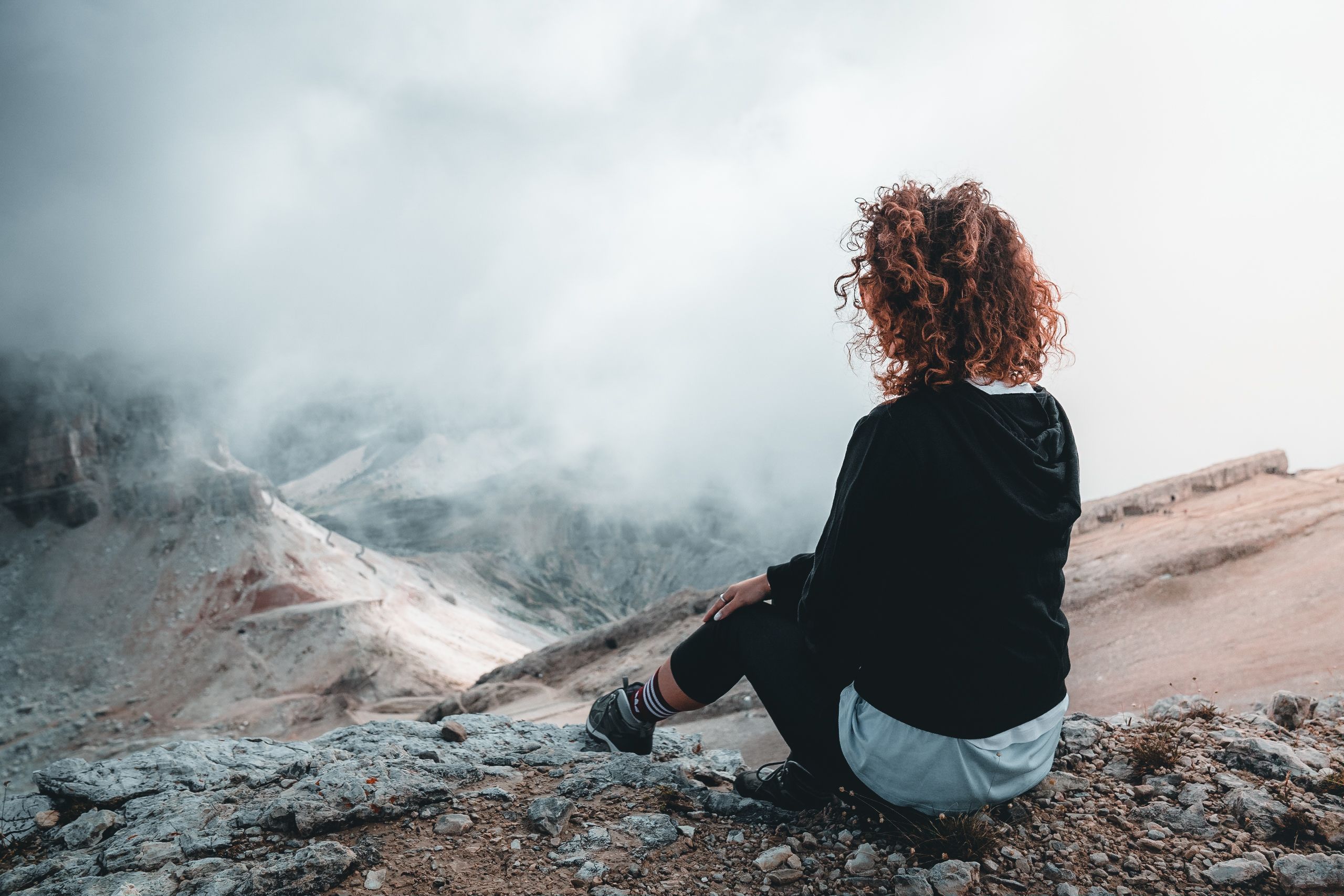 Hiker sitting calmly on rocky terrain enjoying a mountain view while taking a rest break